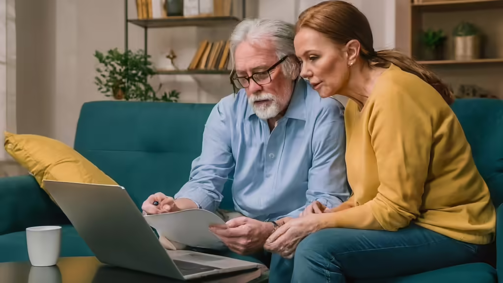 Senior couple checking Medigap insurance costs on a laptop, reviewing rates in their ZIP code.